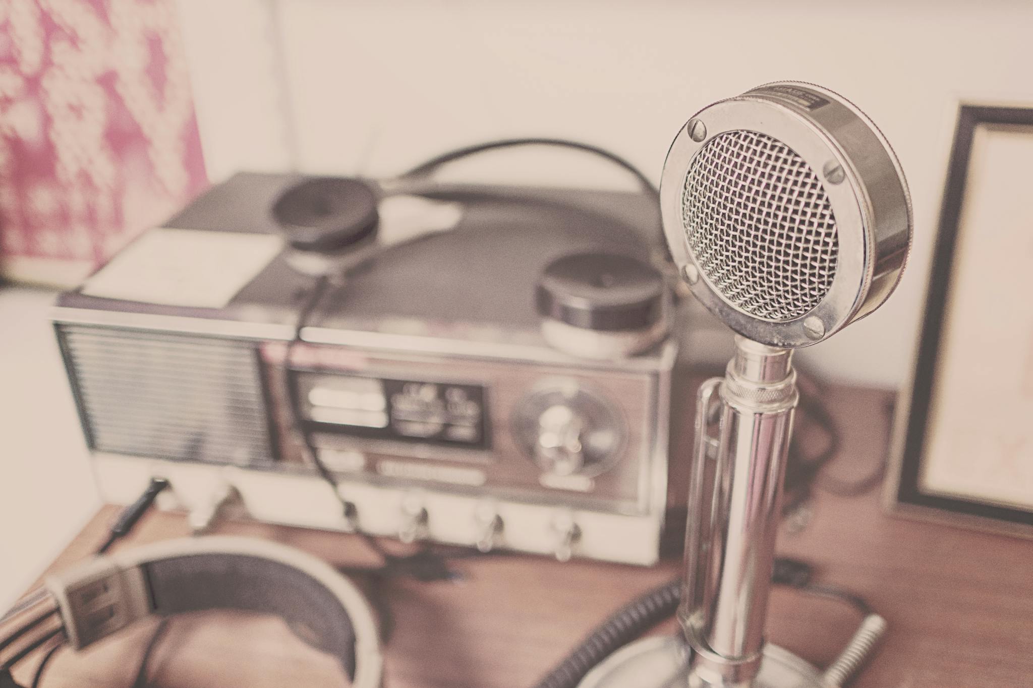 A classic vintage microphone and radio set with headphones displayed on a wooden table.